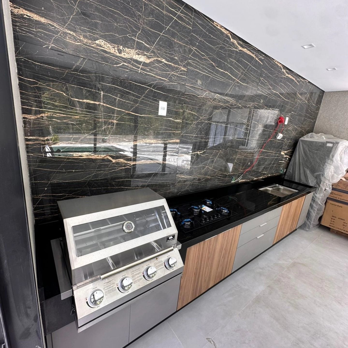 Área gourmet com churrasqueira e bancada em pedra escura